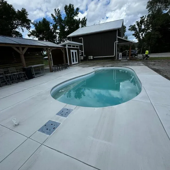 Broom-finished concrete pool deck around a fiberglass pool in a Cincinnati backyard