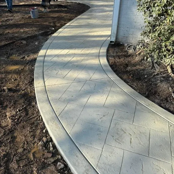 Curved stamped concrete walkway with an ashlar slate pattern beside a home