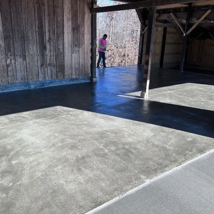 Stained and sealed concrete floor with a dark border under a covered pavilion