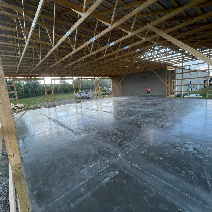 Large troweled concrete floor slab inside a post-frame pole barn