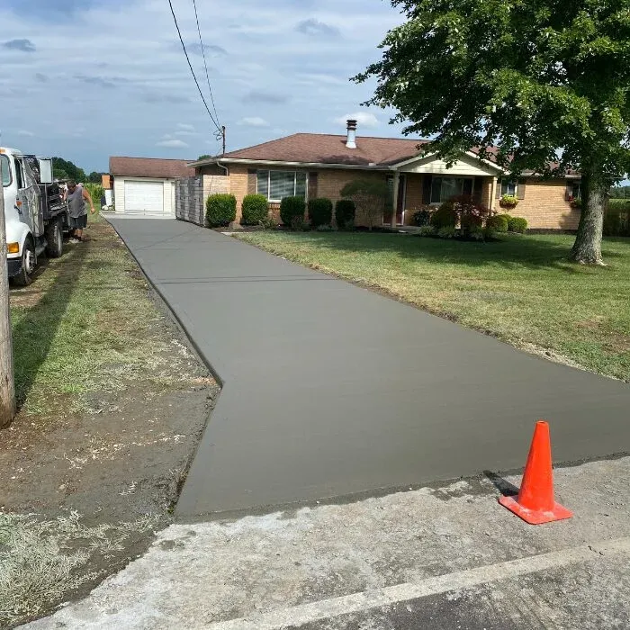 Freshly finished concrete driveway leading to a brick ranch home