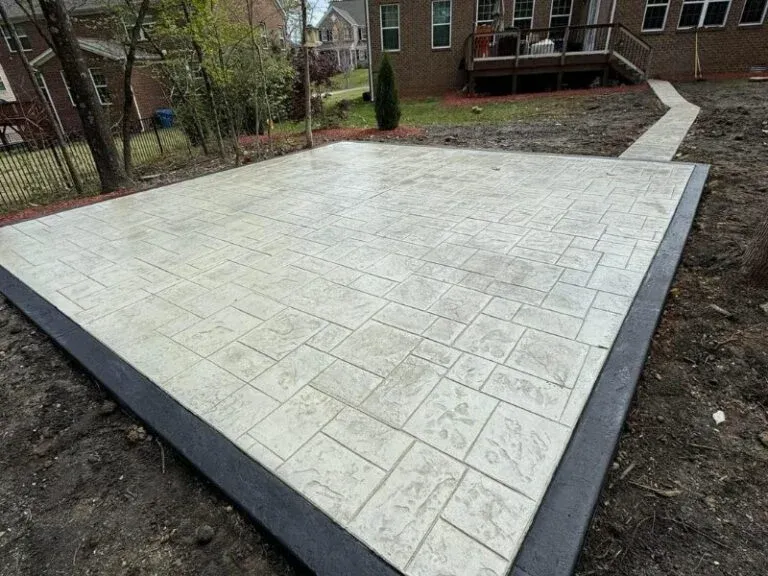 Stamped concrete patio with a dark contrasting border behind a brick home
