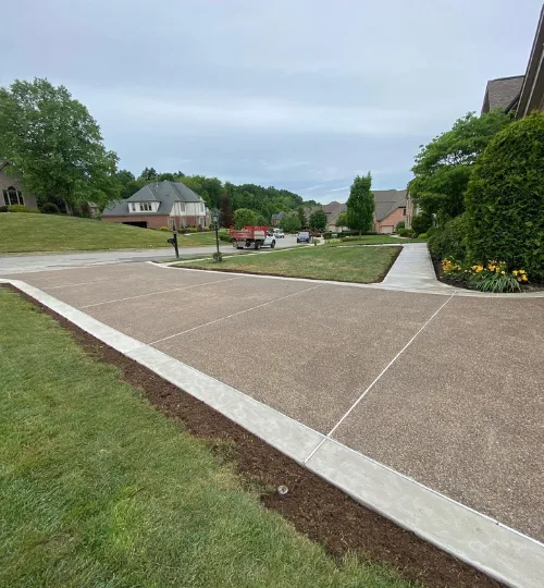 Exposed-aggregate concrete driveway with a smooth banded border in a suburban Cincinnati neighborhood