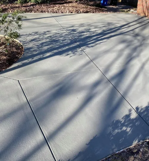 Smooth-finished concrete driveway with control joints and a curved landscaped edge